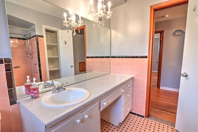 full bath with a notable chandelier, tile walls, wainscoting, and vanity