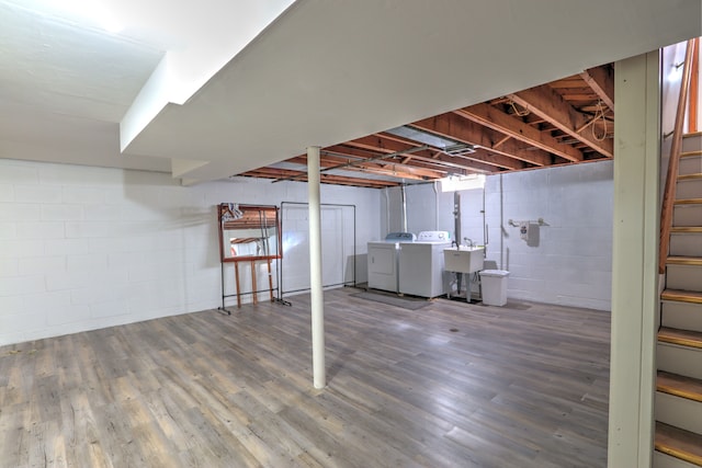 finished below grade area featuring washing machine and clothes dryer, wood finished floors, a sink, concrete block wall, and stairs