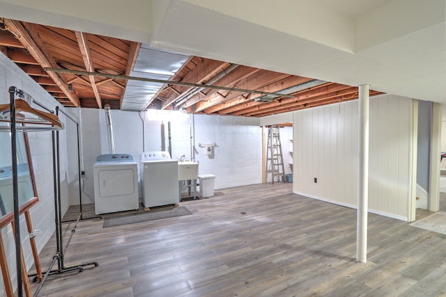 unfinished basement with separate washer and dryer, wood finished floors, and concrete block wall