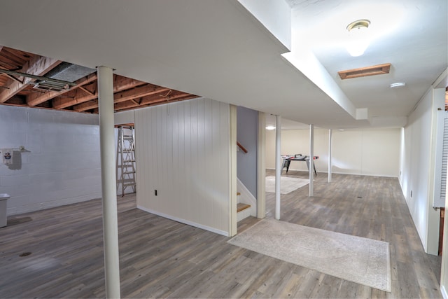 finished below grade area featuring stairs, baseboards, and wood finished floors