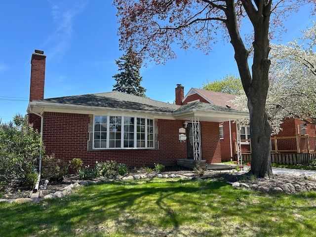 view of front facade featuring brick siding, a front lawn, fence, and a chimney
