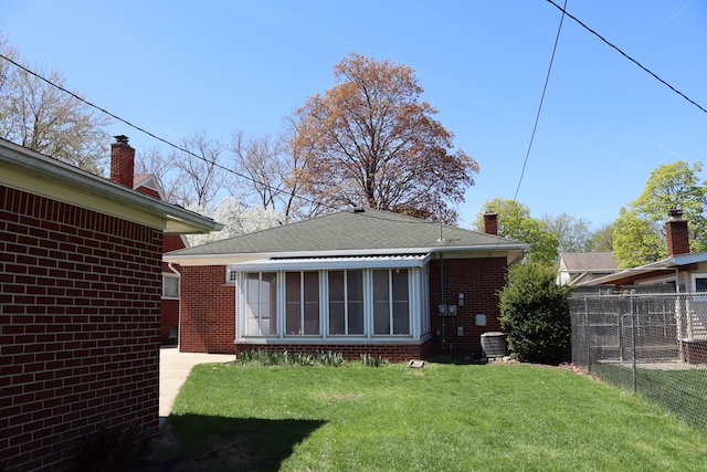 back of house with brick siding, fence, central air condition unit, and a sunroom