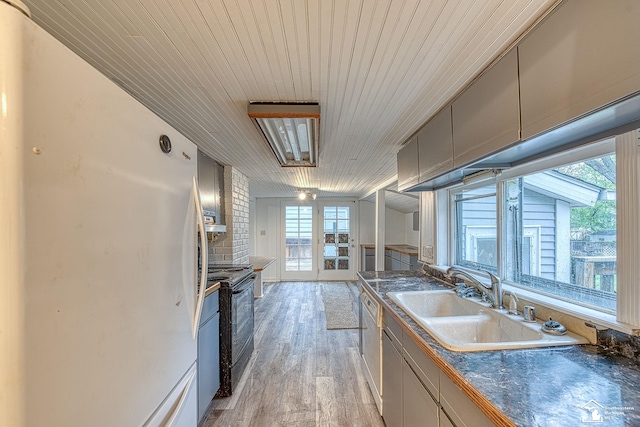 kitchen featuring wooden ceiling, white appliances, light wood-style flooring, dark countertops, and a sink