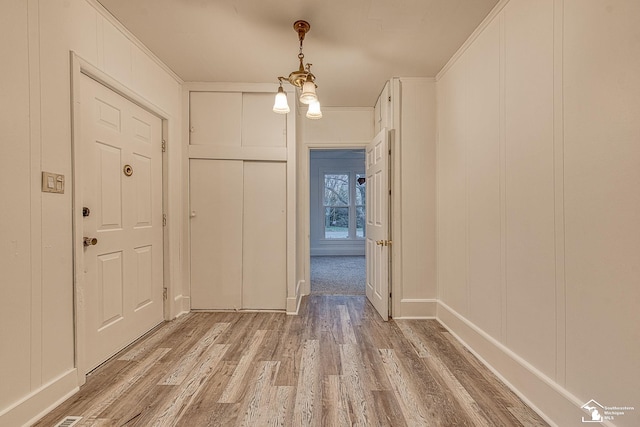 entryway with light wood finished floors and a decorative wall