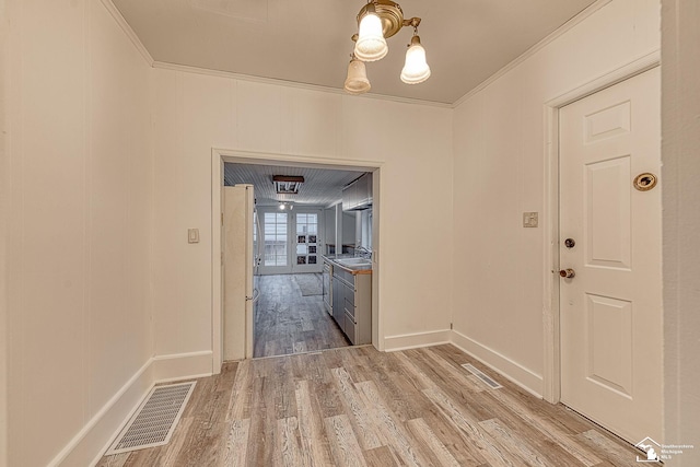 interior space featuring a notable chandelier, visible vents, baseboards, ornamental molding, and wood finished floors