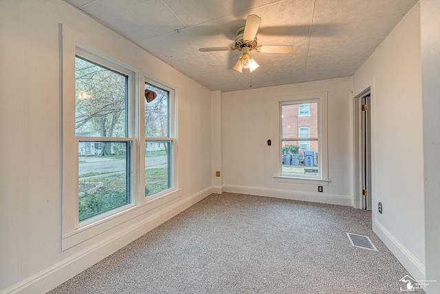 unfurnished room with a ceiling fan, carpet flooring, baseboards, and visible vents