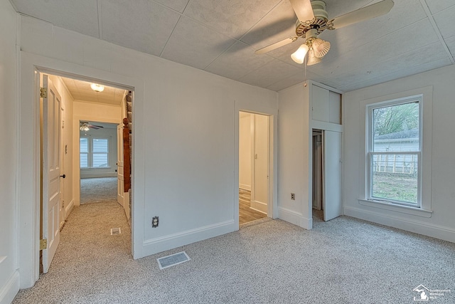 unfurnished bedroom with baseboards, visible vents, light carpet, and multiple windows