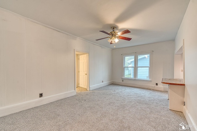 spare room with crown molding, ceiling fan, light carpet, and baseboards
