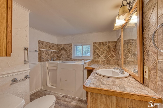 full bathroom featuring vanity, toilet, crown molding, a garden tub, and wood finished floors