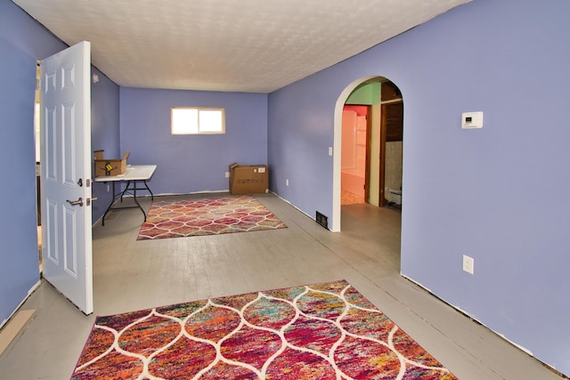 interior space featuring arched walkways, a textured ceiling, and a baseboard radiator