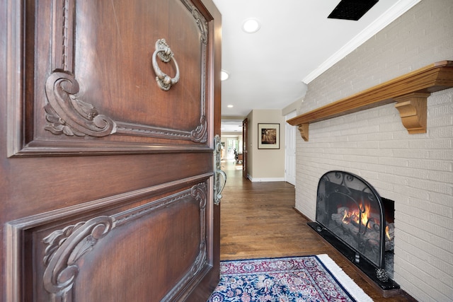 hallway with brick wall, ornamental molding, recessed lighting, baseboards, and dark wood-style floors