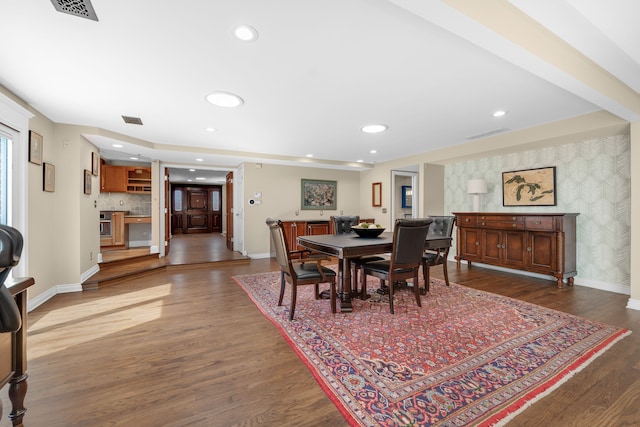 dining space with baseboards, dark wood-style flooring, wallpapered walls, and visible vents