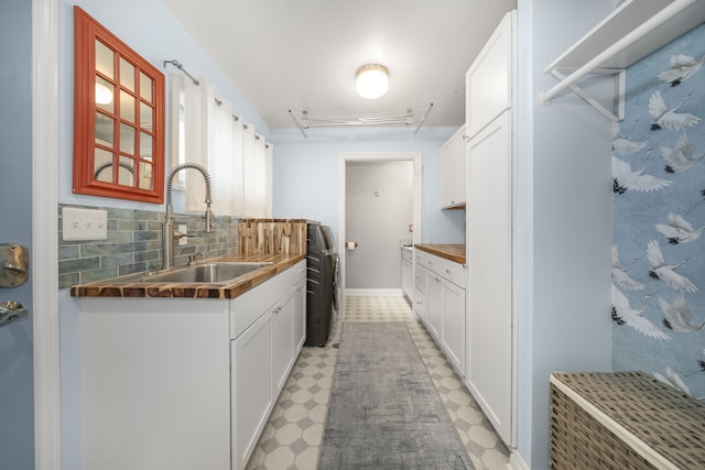 kitchen with a sink, light floors, tasteful backsplash, and white cabinets