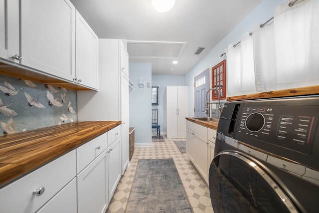 laundry room featuring a sink, attic access, washer / dryer, light floors, and visible vents