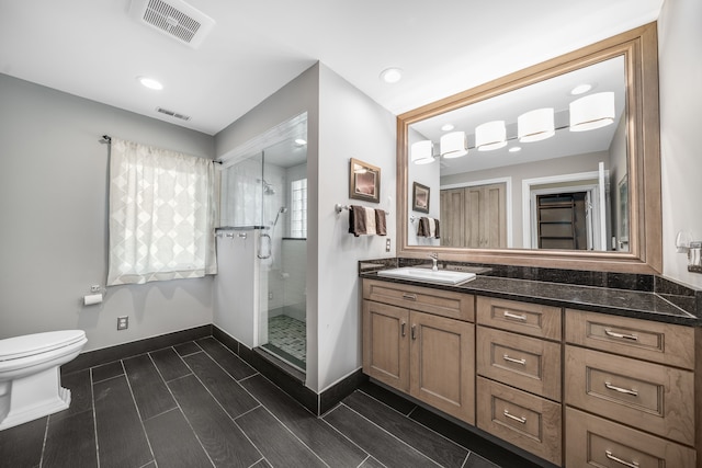 bathroom with vanity, a stall shower, toilet, and visible vents