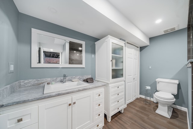 bathroom with visible vents, wood finished floors, vanity, baseboards, and toilet