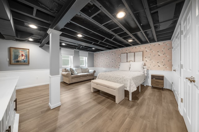 bedroom featuring wallpapered walls, light wood finished floors, and a wainscoted wall
