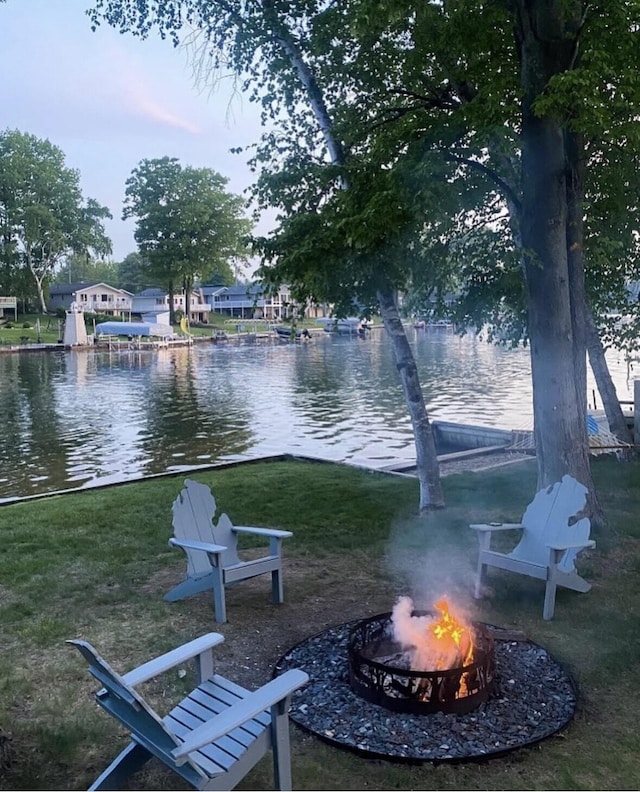surrounding community with a fire pit, a yard, and a water view