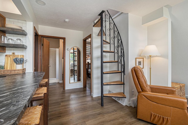 stairway featuring baseboards, wood finished floors, and a textured ceiling