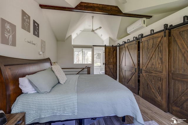 bedroom featuring lofted ceiling with beams, wood finished floors, a wall mounted AC, and a barn door