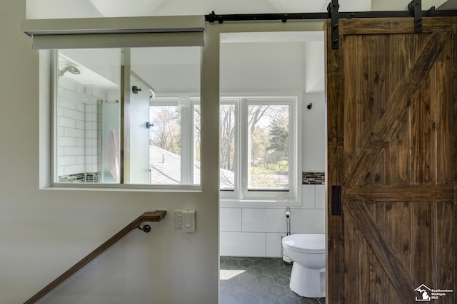 bathroom with tile patterned floors, toilet, and tile walls