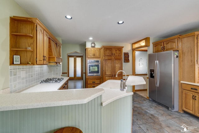 kitchen with decorative backsplash, stainless steel appliances, light countertops, a sink, and a peninsula