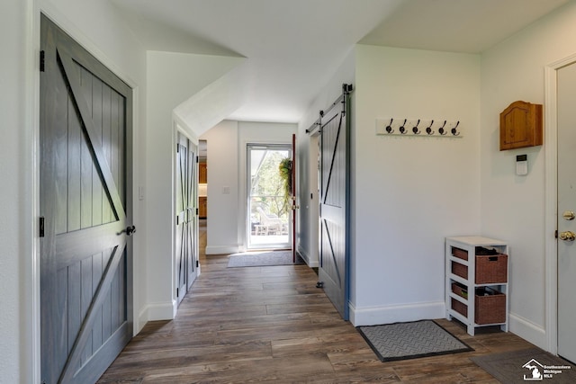 entrance foyer featuring dark wood-style floors, a barn door, and baseboards