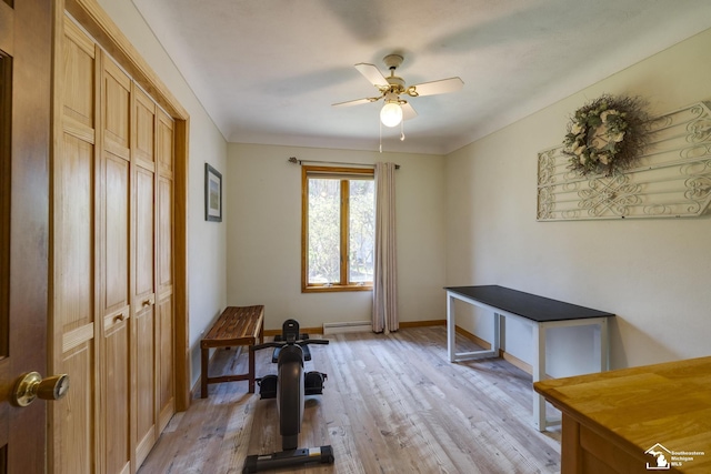 exercise room with a baseboard heating unit, a ceiling fan, light wood-style flooring, and baseboards