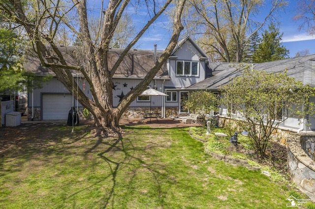 back of property with roof with shingles, a yard, a patio area, and a garage