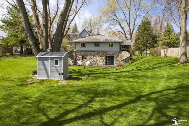 back of house featuring a lawn, an outdoor structure, a shed, and stone siding