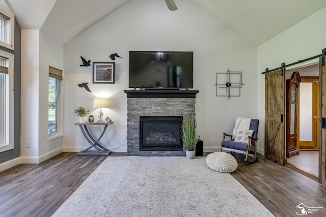 living room with a barn door, a fireplace, high vaulted ceiling, baseboards, and wood finished floors