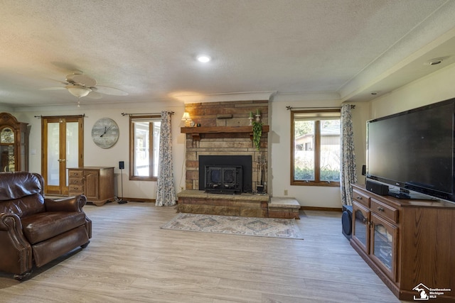 living room featuring crown molding, a textured ceiling, light wood-style floors, and baseboards