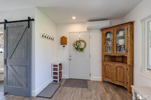 foyer entrance with recessed lighting, wood finished floors, a barn door, an AC wall unit, and baseboards