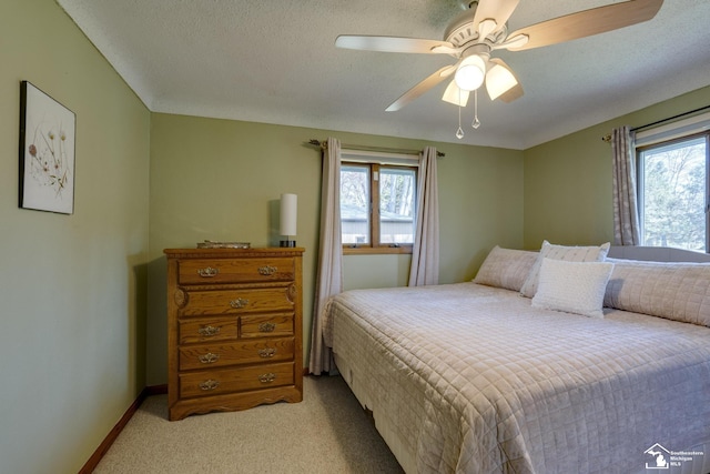 bedroom with light colored carpet, ceiling fan, baseboards, and multiple windows