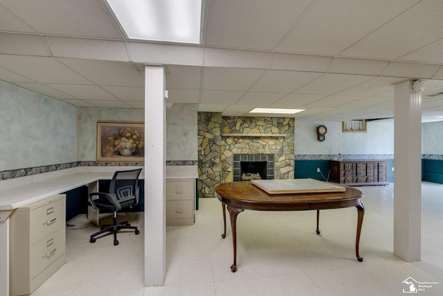 home office featuring light floors, a drop ceiling, a fireplace, and wallpapered walls
