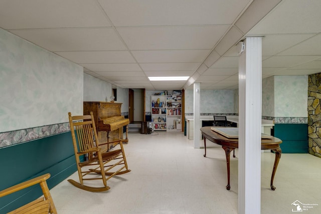 sitting room with tile patterned floors, a paneled ceiling, a wainscoted wall, and wallpapered walls