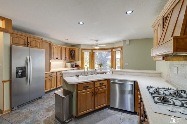 kitchen featuring tasteful backsplash, stainless steel appliances, light countertops, ceiling fan, and a sink
