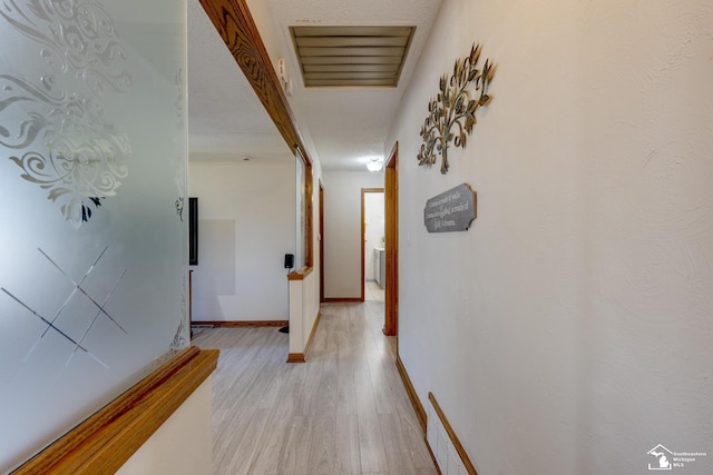 hall featuring visible vents, light wood-style flooring, and baseboards
