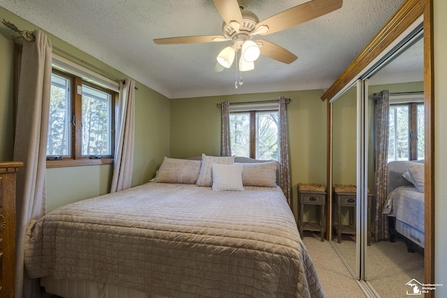bedroom with multiple windows, light colored carpet, a textured ceiling, and a closet