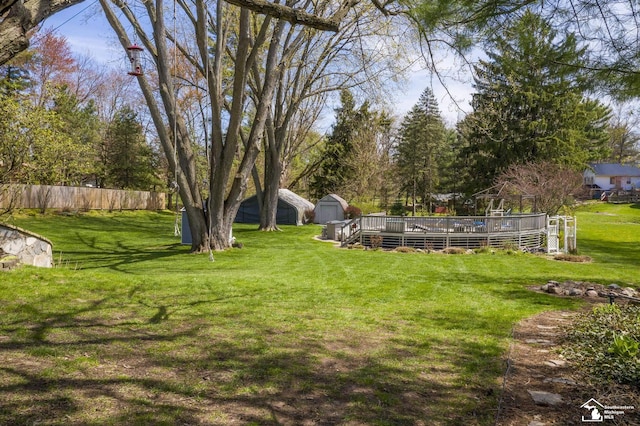 view of yard with an outdoor structure, a shed, a deck, and fence