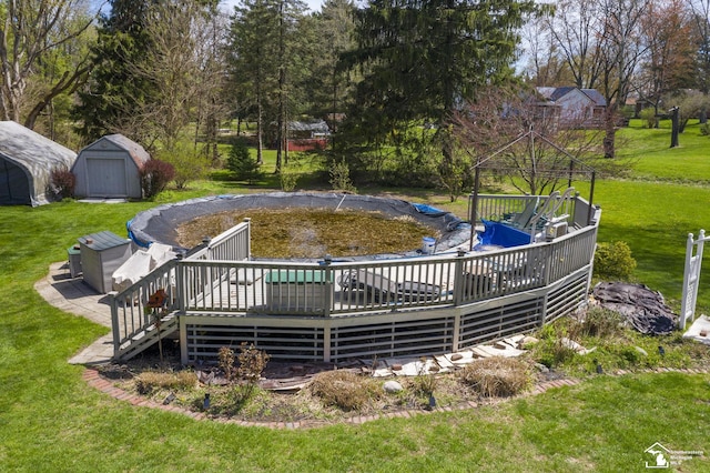 view of pool with an outbuilding, a shed, a deck, and a lawn