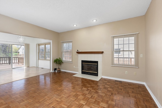 30701 Sandalwood Cir, Novi, MI 48377 - unfurnished living room with a tiled fireplace, an inviting chandelier, baseboards, visible vents, and a textured ceiling