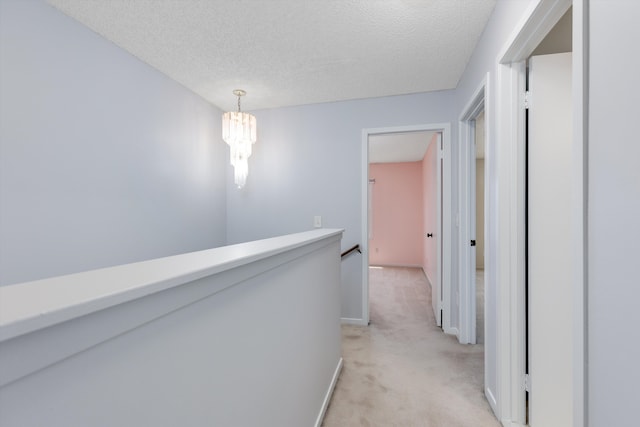 30701 Sandalwood Cir, Novi, MI 48377 - hallway featuring an inviting chandelier, an upstairs landing, light carpet, baseboards, and a textured ceiling