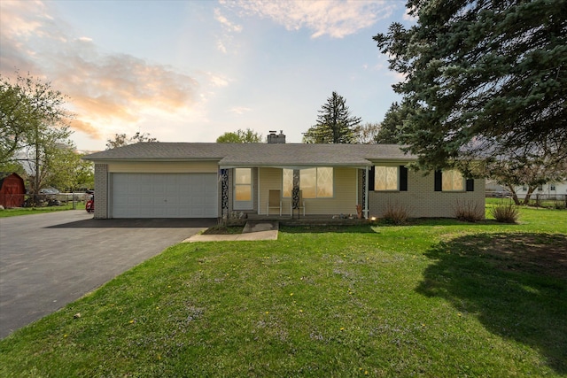 single story home featuring aphalt driveway, covered porch, a chimney, an attached garage, and a yard