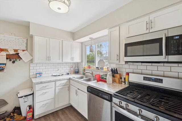 kitchen featuring a sink, appliances with stainless steel finishes, white cabinets, and light countertops