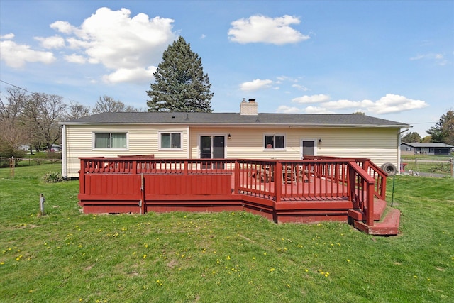 back of house featuring a lawn, a wooden deck, and a chimney