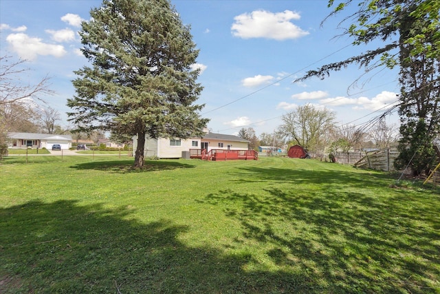 view of yard featuring an outbuilding, fence, a wooden deck, and a storage unit
