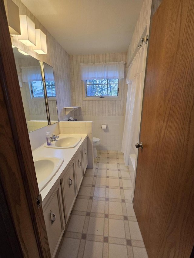 609 1st St, Lake Odessa, MI 48849 - bathroom with toilet, tile walls, a sink, and double vanity