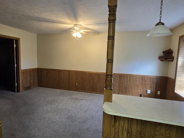 609 1st St, Lake Odessa, MI 48849 - unfurnished living room featuring carpet floors, wainscoting, wood walls, visible vents, and a ceiling fan