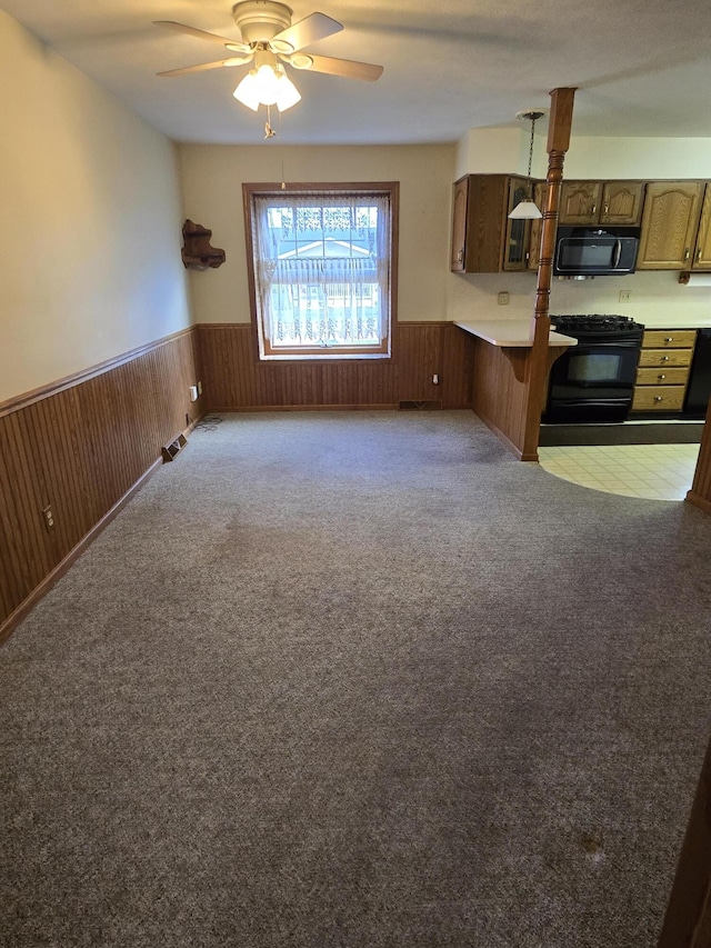 609 1st St, Lake Odessa, MI 48849 - interior space featuring a breakfast bar area, wainscoting, black appliances, a ceiling fan, and open floor plan